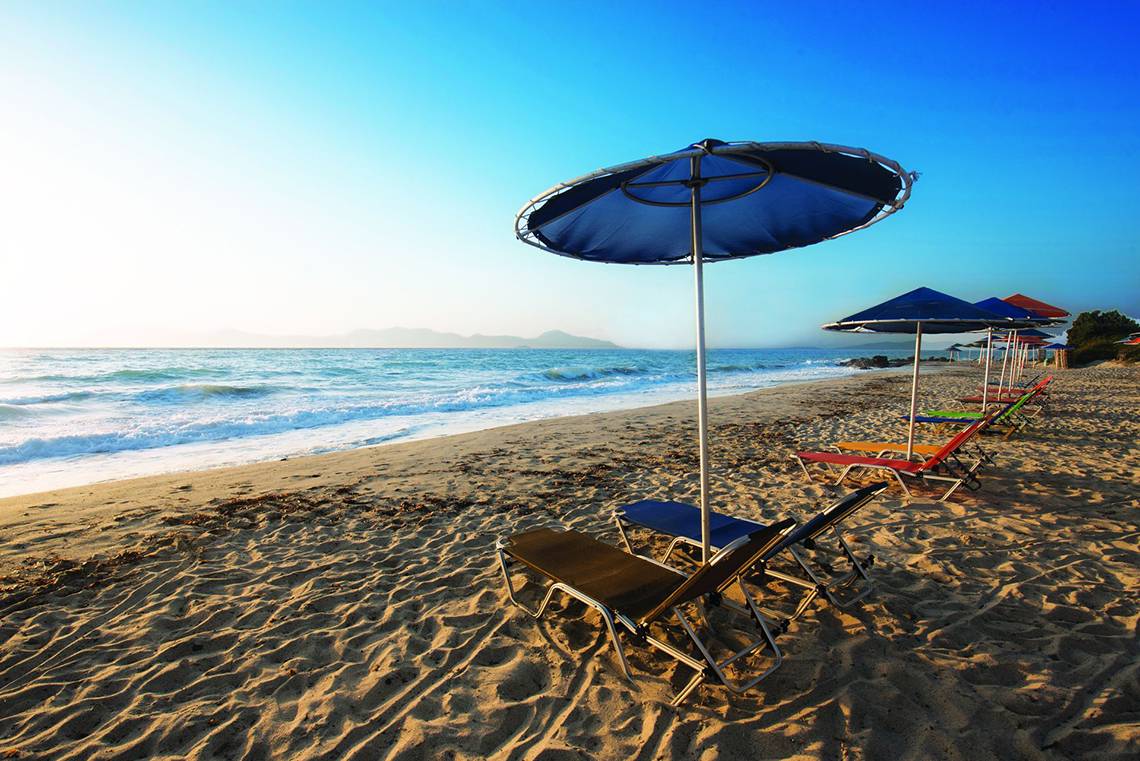 Sonnenliegen und Sonnenschirme am Strand des Eurovillage Achilleas Hotels