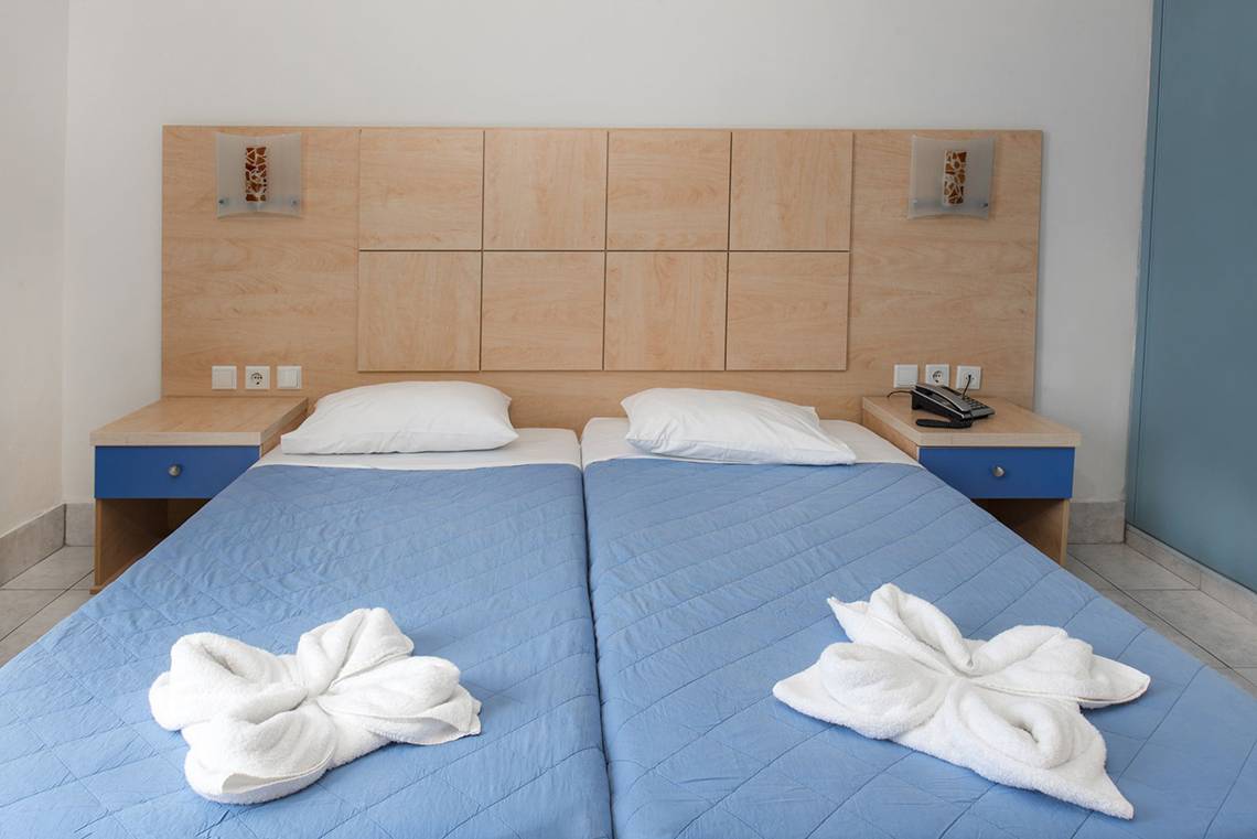 Doppelbett im Hotelzimmer Eurovillage Achilleas mit zwei Kissen und weißen Handtüchern
