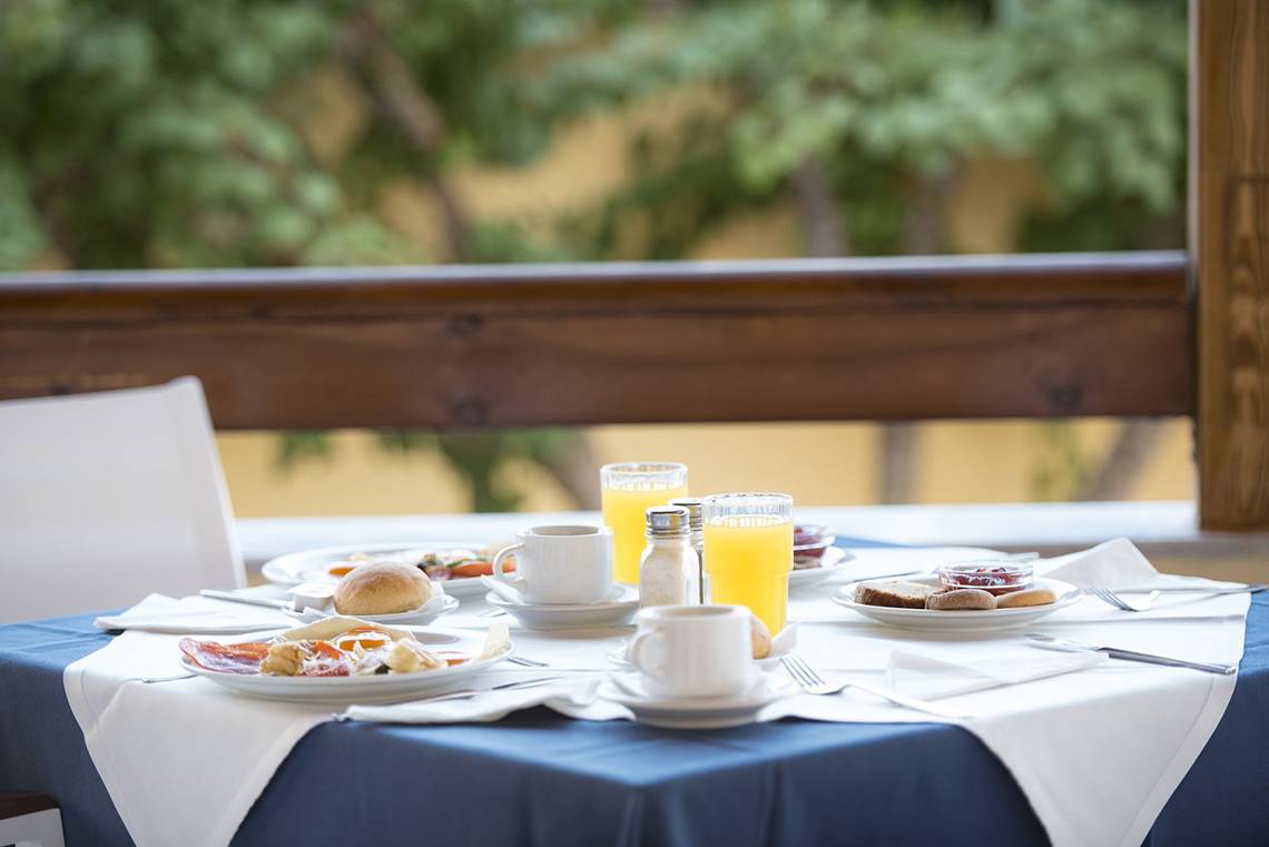 Frühstückstisch im Eurovillage Achilleas Hotel mit Speisen, Getränken und Geschirr.