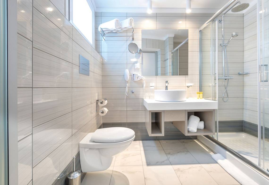 Badezimmer im Eurovillage Achilleas Hotel mit moderner Einrichtung und Glasdusche.