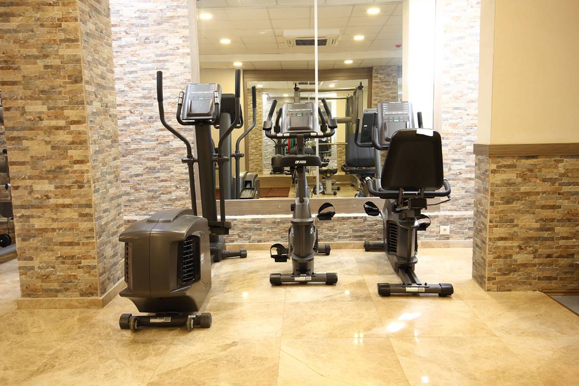Fitnessbereich im Dalyan Resort Hotel mit mehreren Trainingsgeräten und einem großen Spiegel.