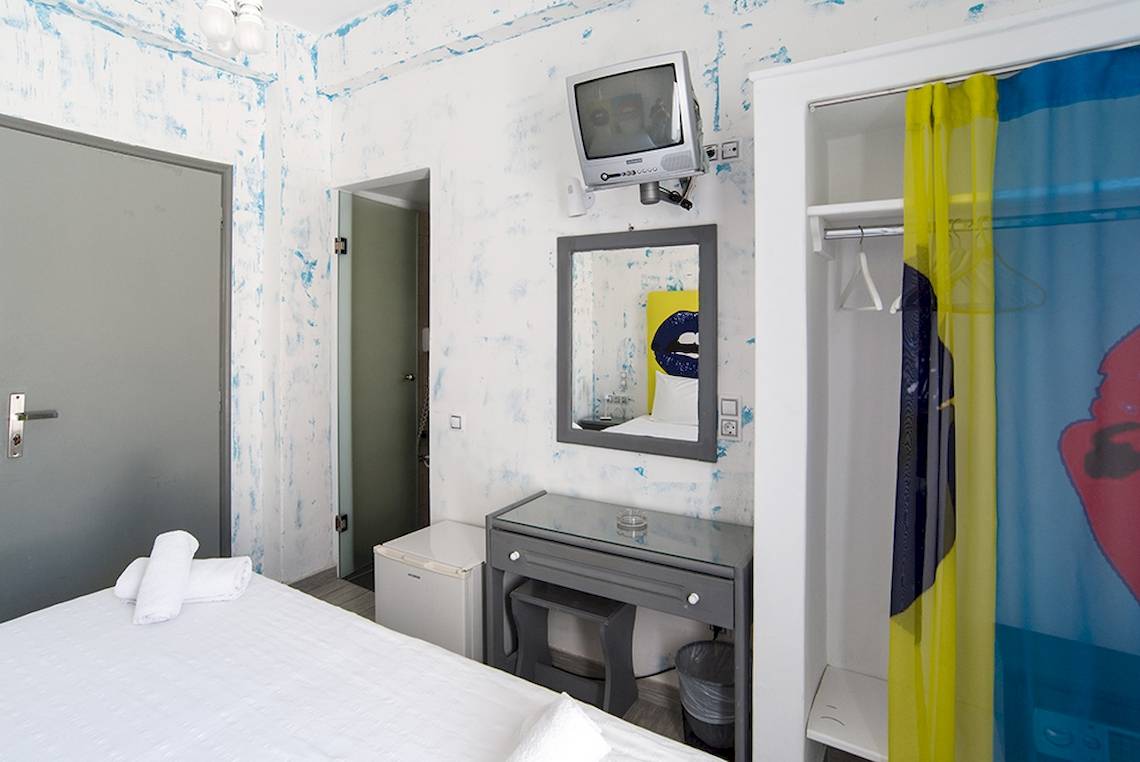 Ein Zimmer im Beach Boutique Hotel mit weißem Bett, blau und weiß gestrichenen Wänden und einer Kommode.