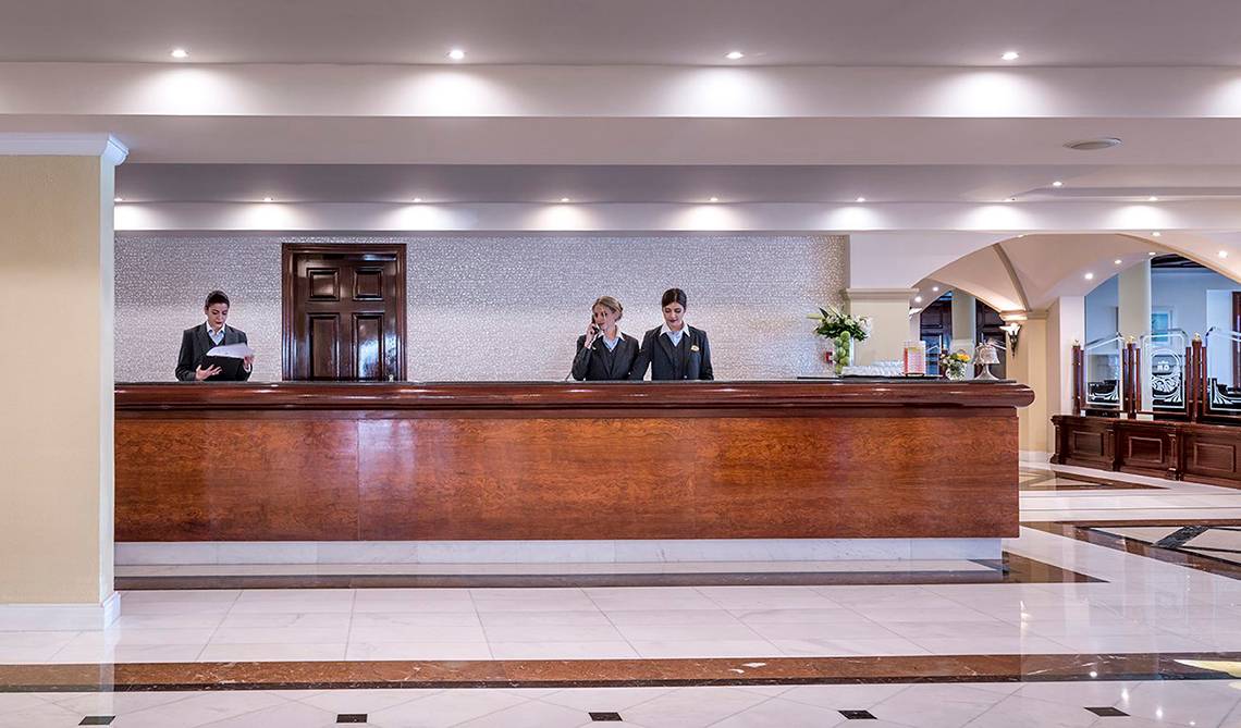 Empfangsbereich des Mitsis Grand Hotel Beach mit zwei Mitarbeiterinnen am Empfangsschalter.
