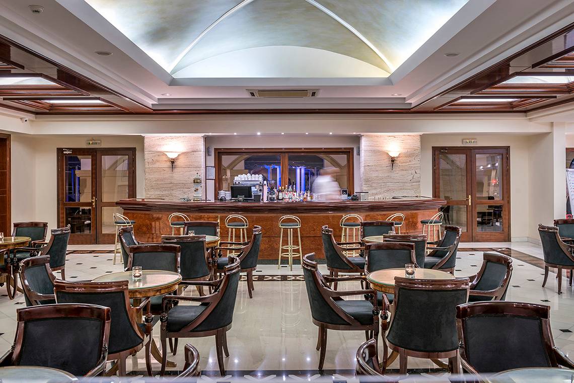 Innenansicht der Bar im Mitsis Grand Hotel Beach mit Theke und Sitzgelegenheiten.