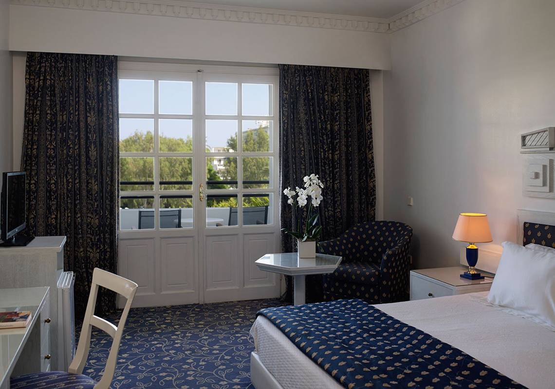 Ein elegant eingerichtetes Hotelzimmer mit Doppelbett, Tisch, Stuhl und Fernseher.