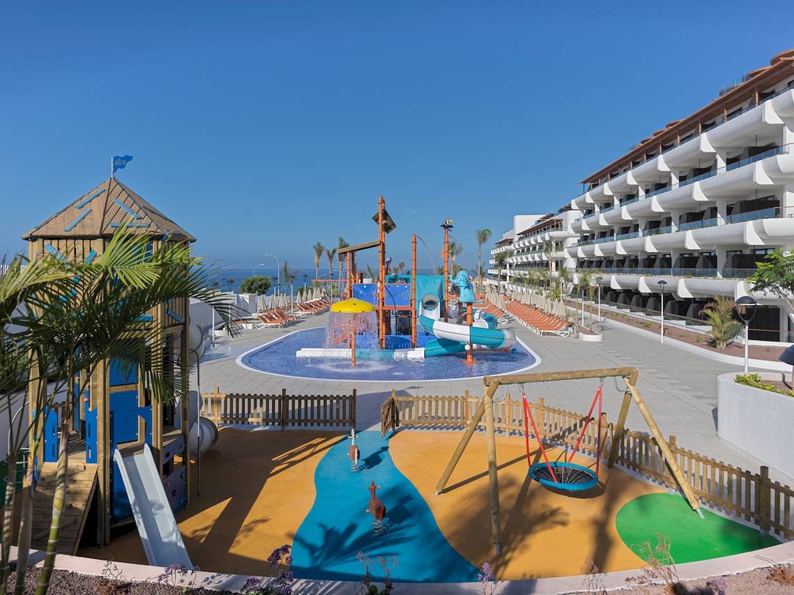 Außenbereich des H10 Atlantic Sunset Hotels mit einem großen Kinderspielplatz, Wasserrutschen und einer Wasserfontäne.
