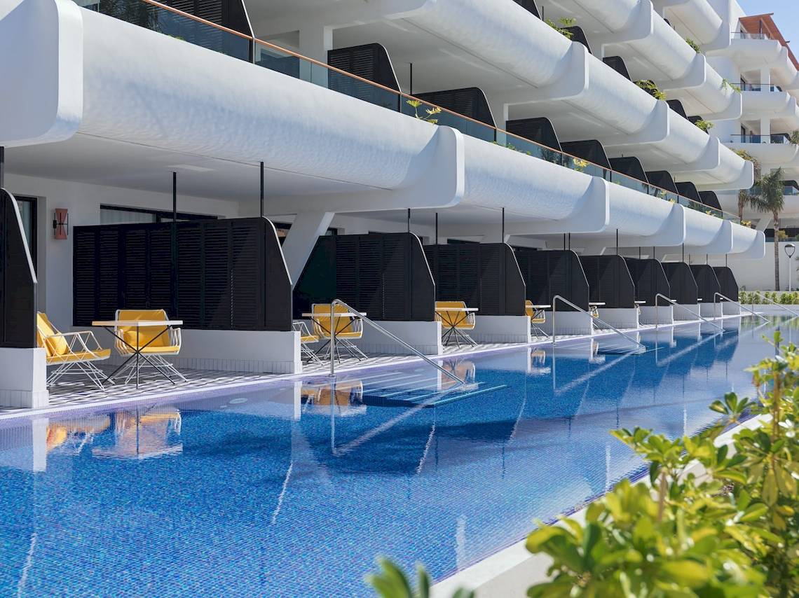 Außenpool des H10 Atlantic Sunset Hotels mit gelben Stühlen und modernen Gebäuden im Hintergrund.
