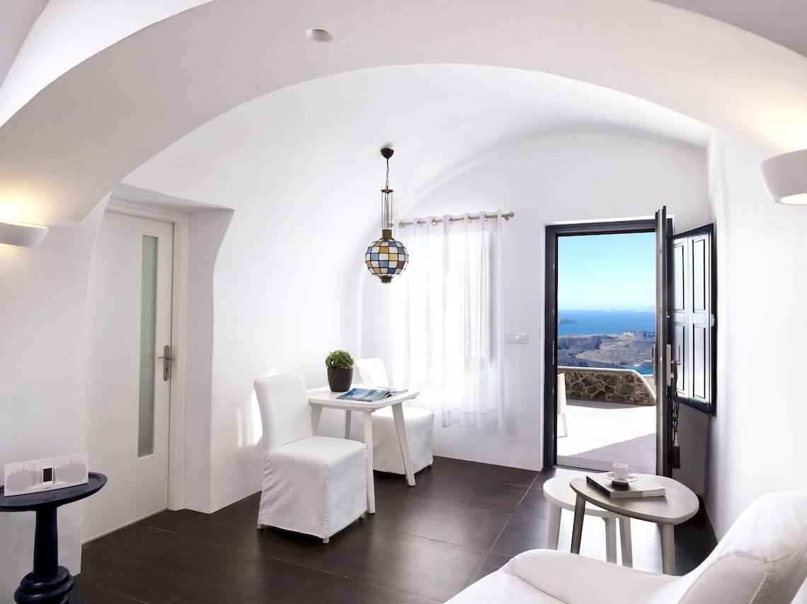 Innenraum von Katikies Chromata Santorini mit weißem Interieur, Tisch, Stühlen und Blick auf das Meer.