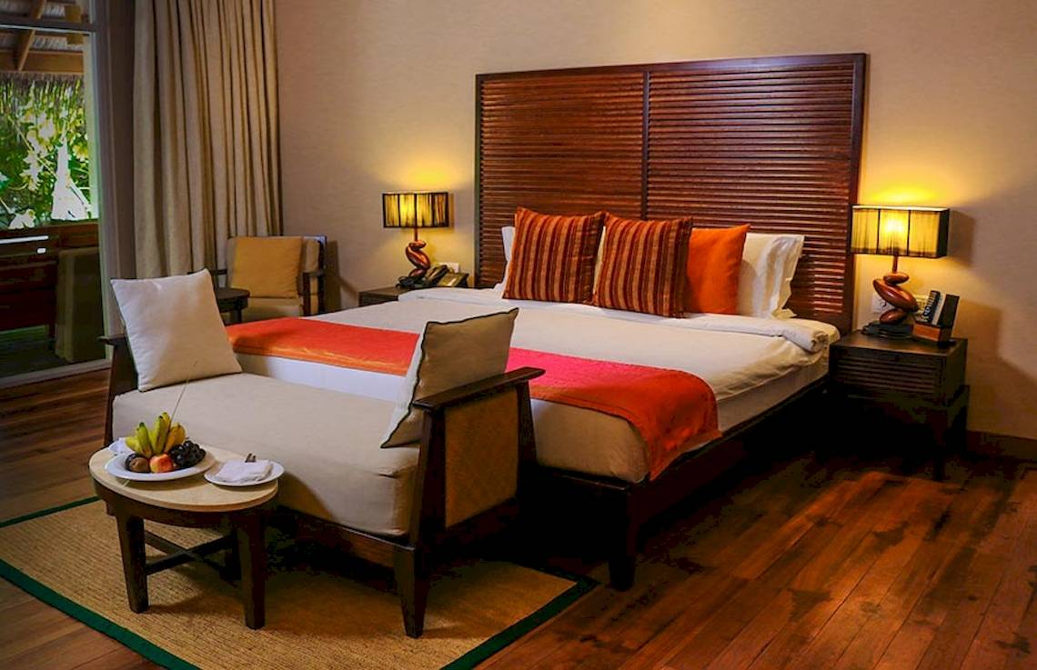 Luxuriöses Hotelzimmer im Nova Maldives mit Bett, Früchten und Deko.