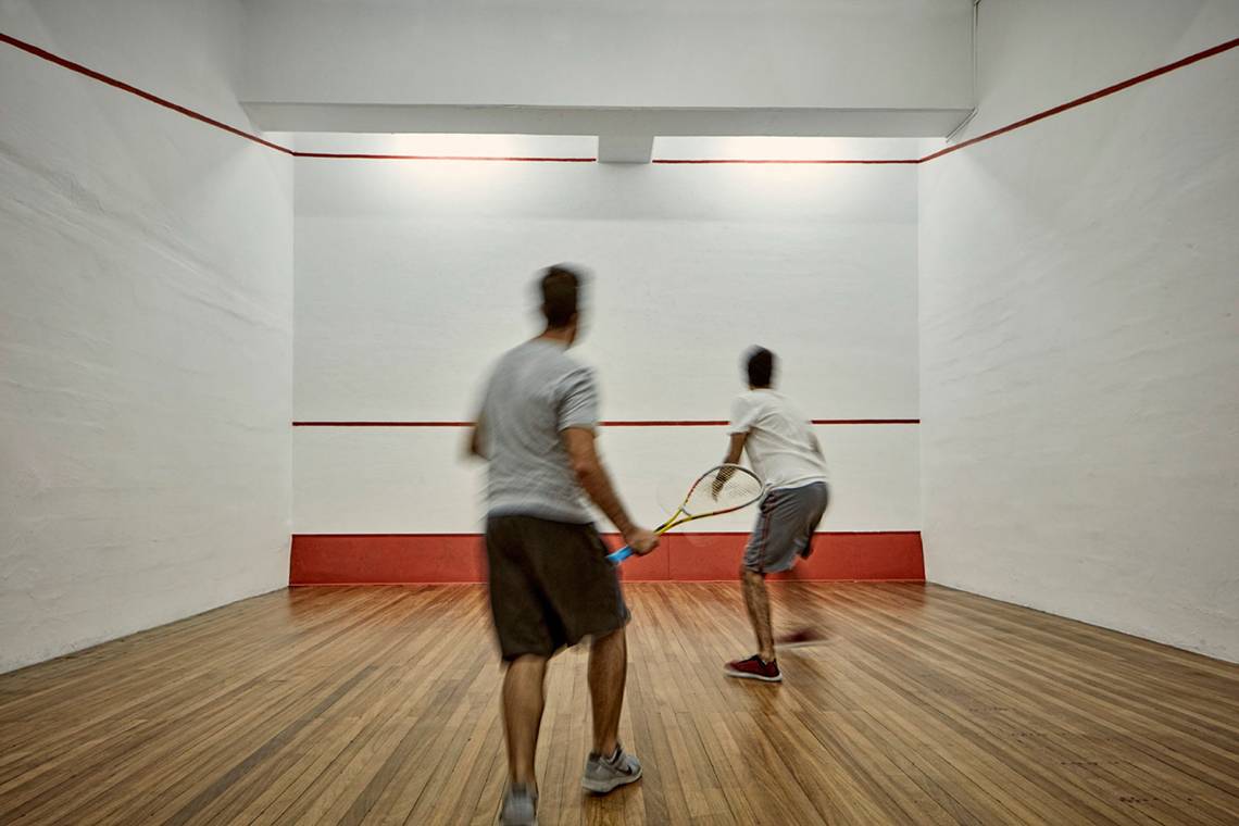 Zwei Männer spielen Badminton in einem gut beleuchteten, quadratischen Raum im Grecian Bay Hotel.
