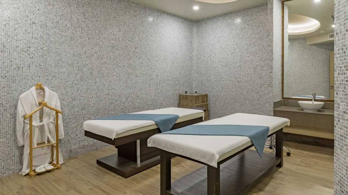 Behandlungsraum im Royal Seginus Hotel mit zwei Massagetischen und einem Bademantelhaken.