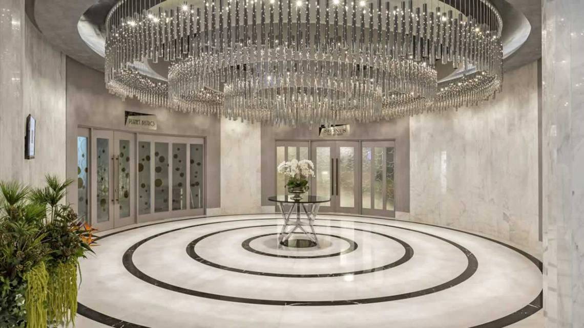 Empfangsbereich des Royal Seginus Hotels mit großem Kristallkronleuchter und moderner Inneneinrichtung.
