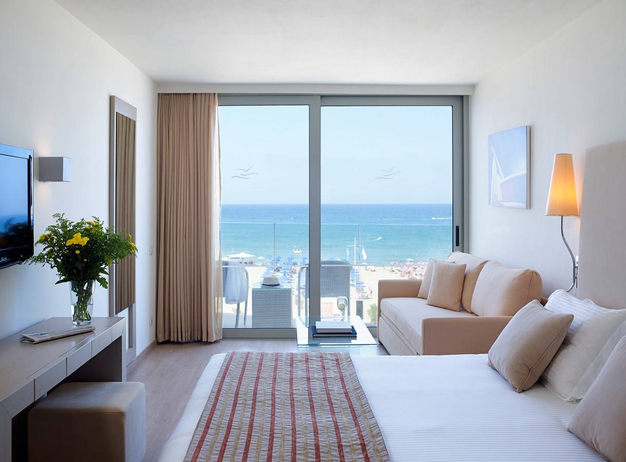 Hotelzimmer im Kriti Beach mit Meerblick, inklusive Sofa, Bett, Fernseher und Dekor.