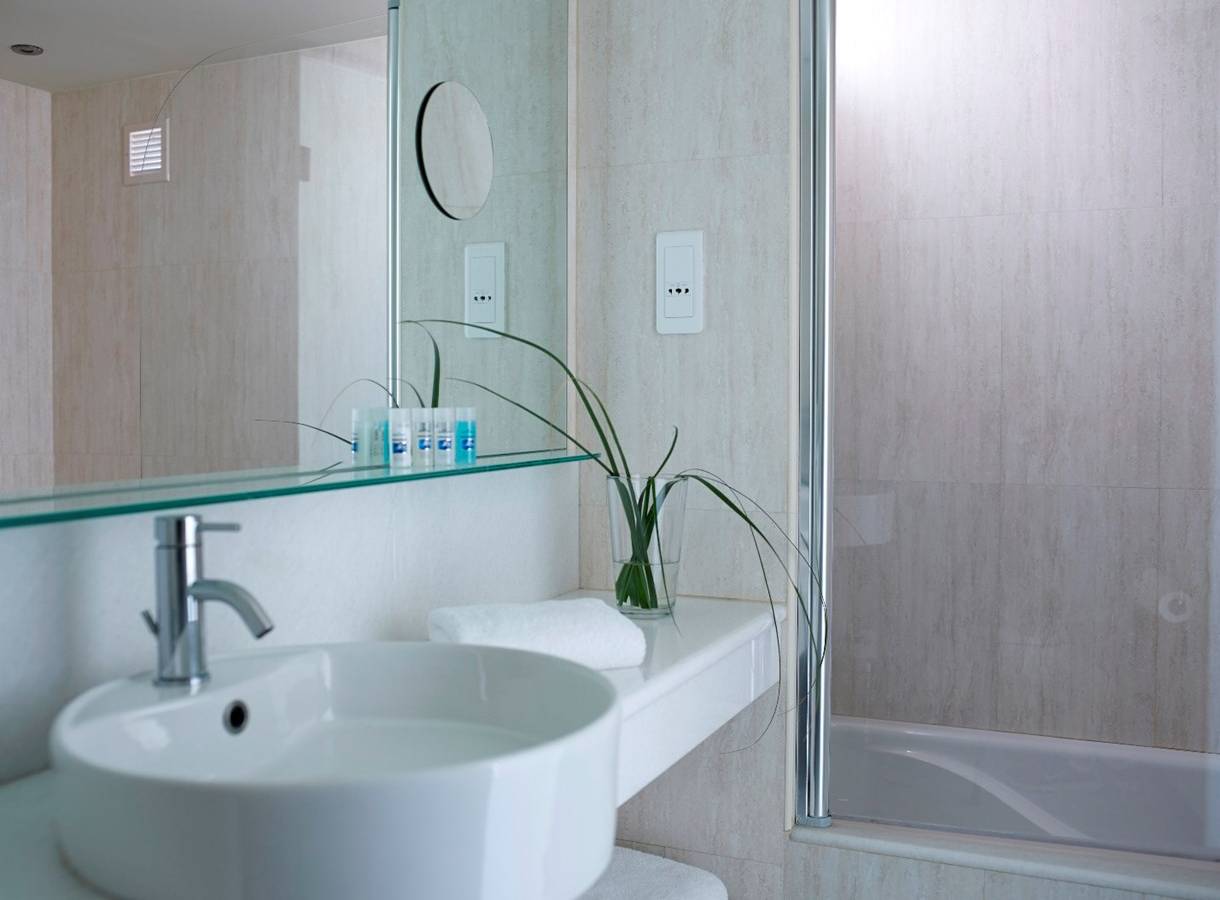 Kriti Beach Hotel Badezimmer mit einer weißen Wanne, einem Waschbecken und einem Spiegel.