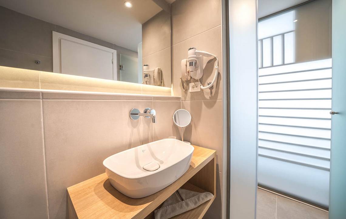 Badezimmer im Adele Beach Hotel mit Waschbecken, Spiegel und Föhn