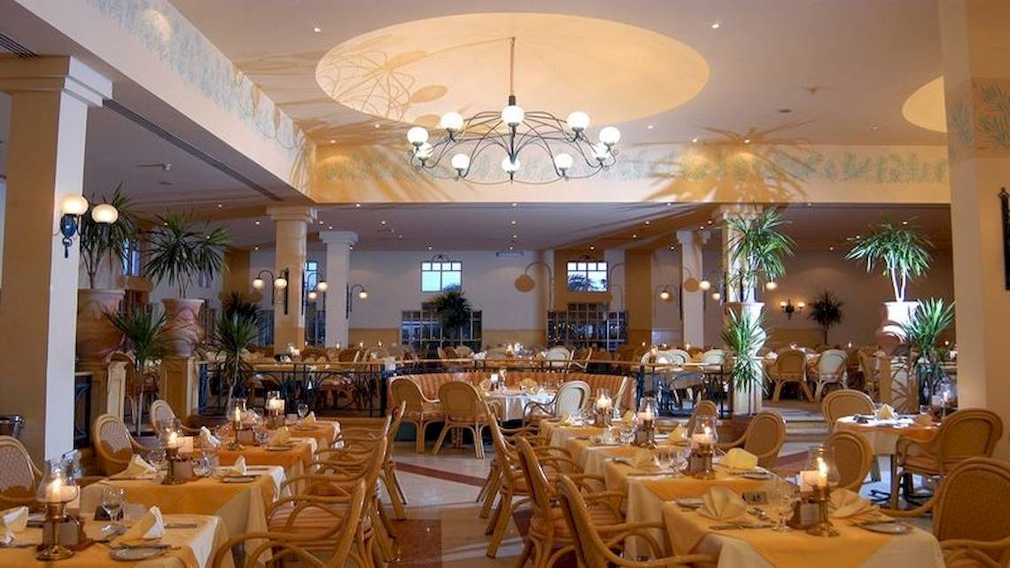 Restaurant im Mövenpick Resort & Spa El Gouna mit gedeckten Tischen, Stühlen, Kronleuchtern und Pflanzen.