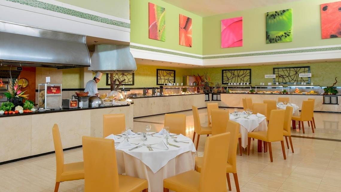 Innenansicht des Restaurants im Grand Sirenis Riviera Maya Resort & Spa mit Buffet, Kellner und gedeckten Tischen.