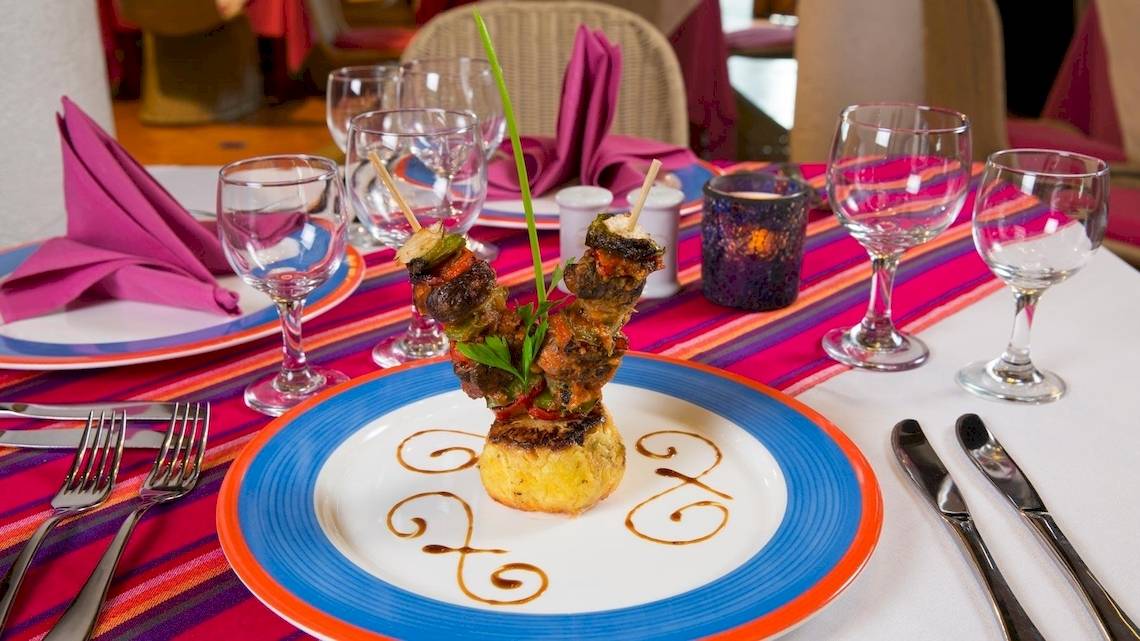 Gedeckter Tisch im Grand Sirenis Riviera Maya Resort & Spa mit einem Gericht auf einem farbenfrohen Teller.