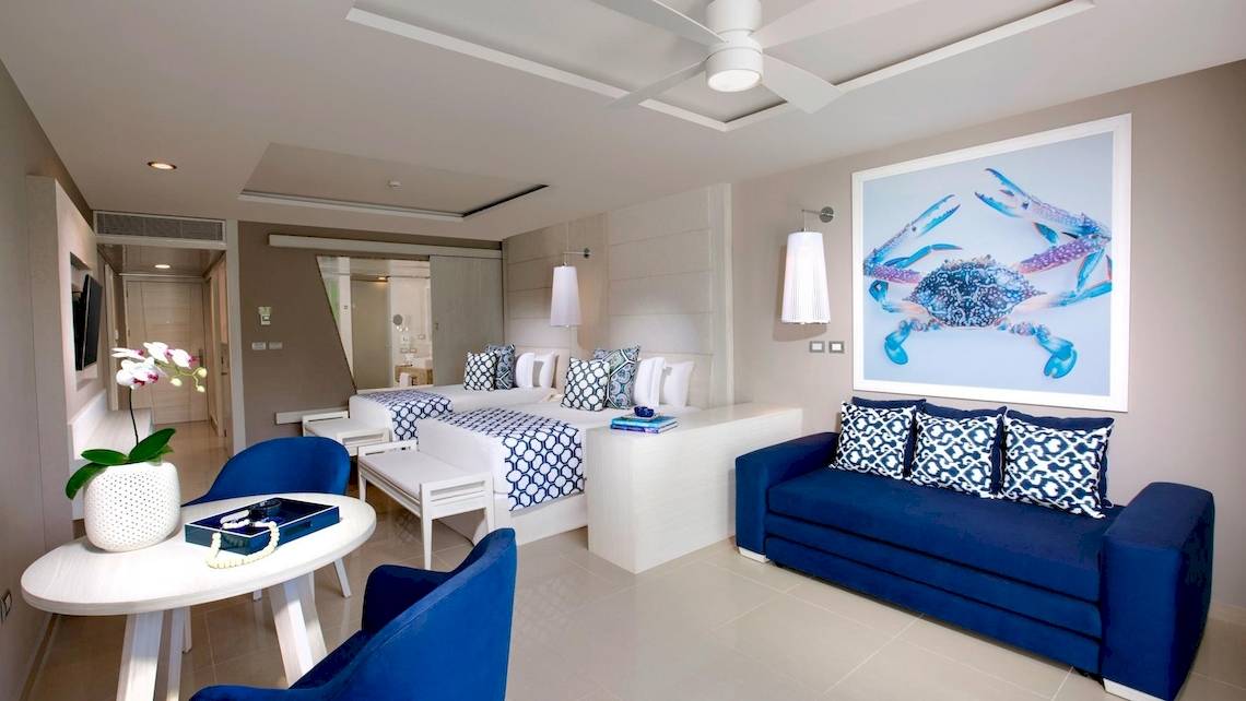 Innenansicht einer Suite im Grand Sirenis Riviera Maya Resort mit blauen Möbeln und einem großen Bild von einem Krebs.