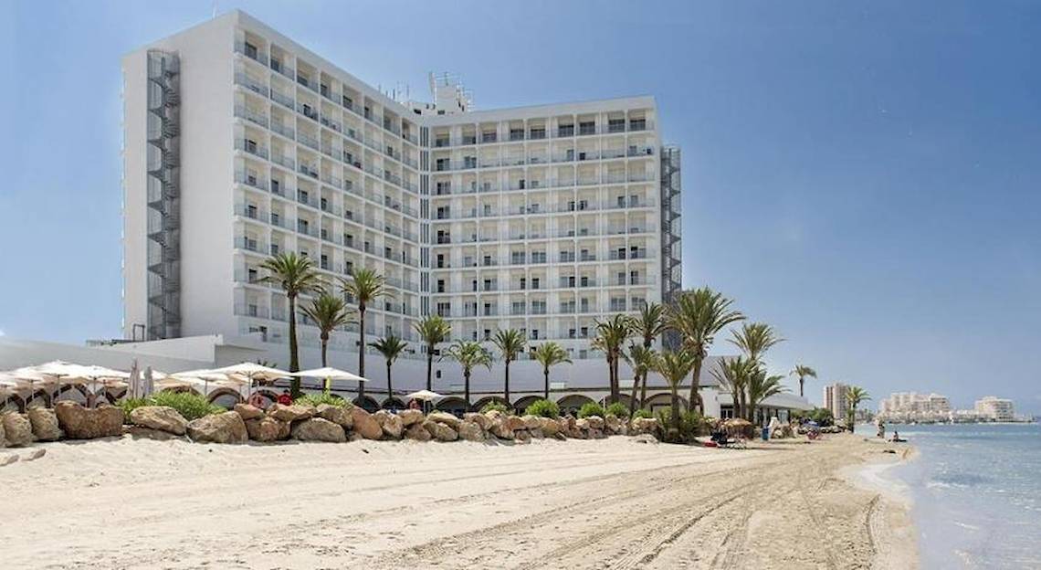 Außenansicht des Roc Barlovento Hotels am Strand mit vielen Palmen und einem blauen Himmel.