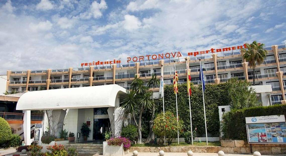 Außenansicht des Roc Barlovento Hotels mit rotem Schriftzug und Flaggen vor dem Gebäude.