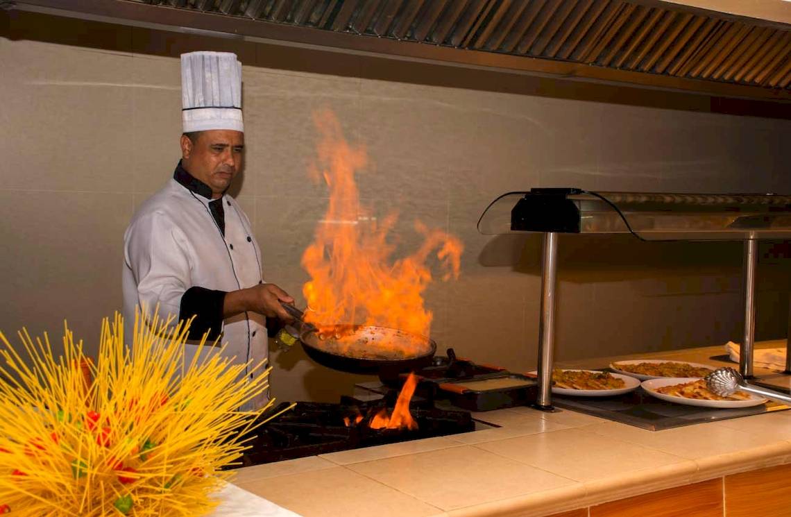 Koch im Roc Barlovento Hotel brät Speisen in einer Pfanne mit Flammen