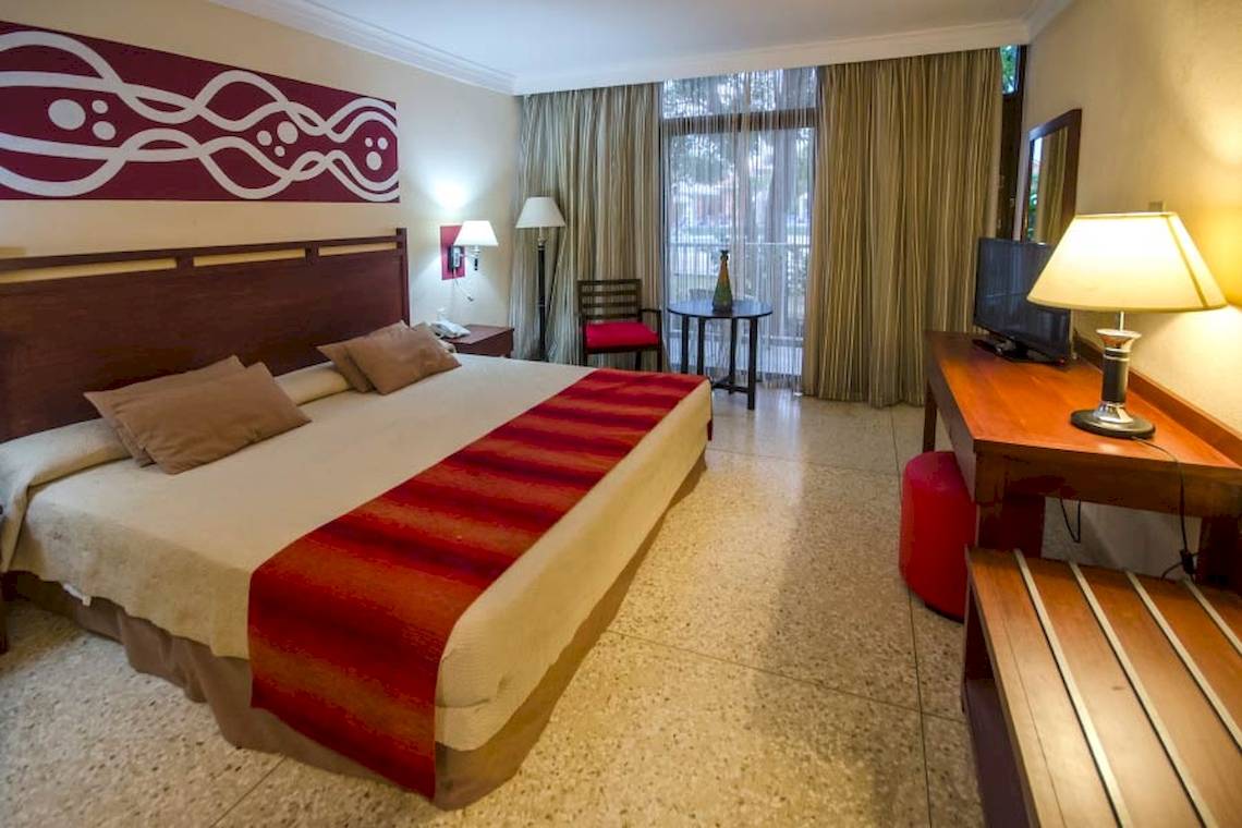 Hotelzimmer im Roc Barlovento mit Doppelbett, Fernseher, Nachttischen und Dekor.