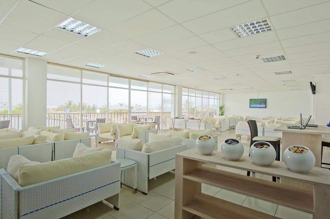Hotellobby von Kuramathi Maldives mit weißen Möbeln und großen Fenstern.