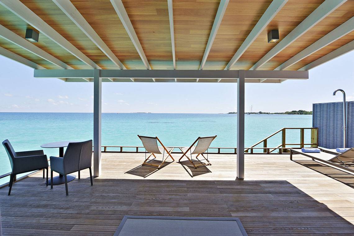 Terrasse im Kuramathi Maldives Hotel mit Blick auf das Meer und zwei Liegestühlen