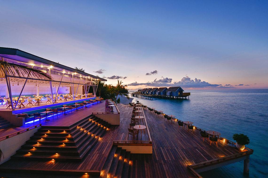 Außenterrasse des Kuramathi Maldives Hotels bei Sonnenuntergang mit Blick auf das Meer.