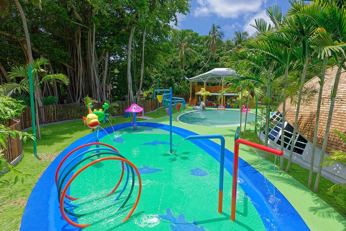 Spielplatz im Kuramathi Maldives Hotel mit bunten Wasserspielen und einer runden Rutsche.