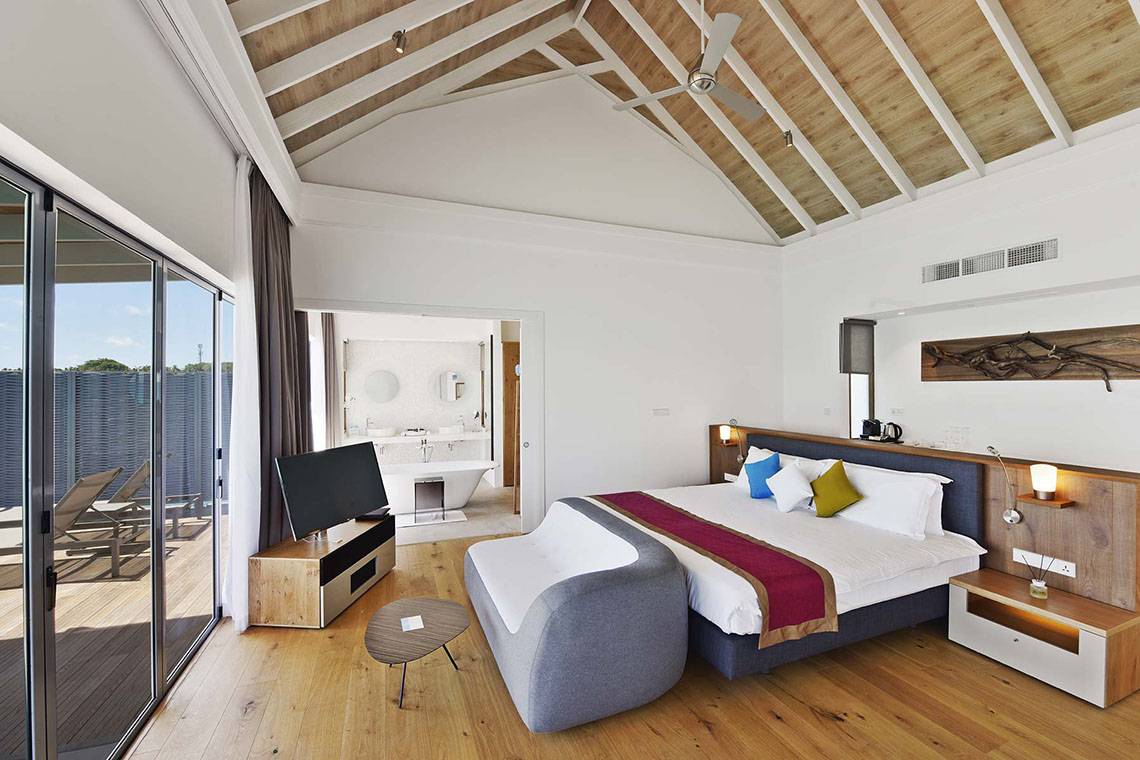 Innenansicht eines Zimmers im Kuramathi Maldives Hotel mit Doppelbett, Fernseher und Balkon