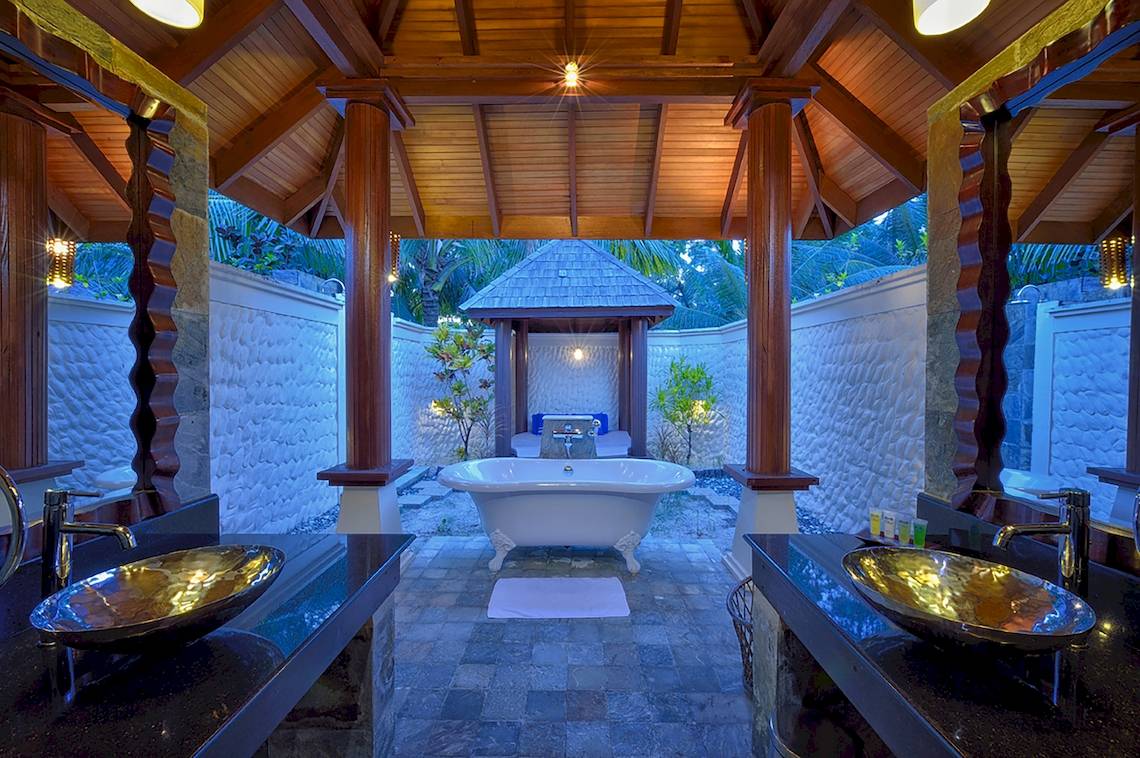 Ein Badezimmer mit freistehender Badewanne und zwei Waschbecken im Freien, Sun Siyam Olhuveli.