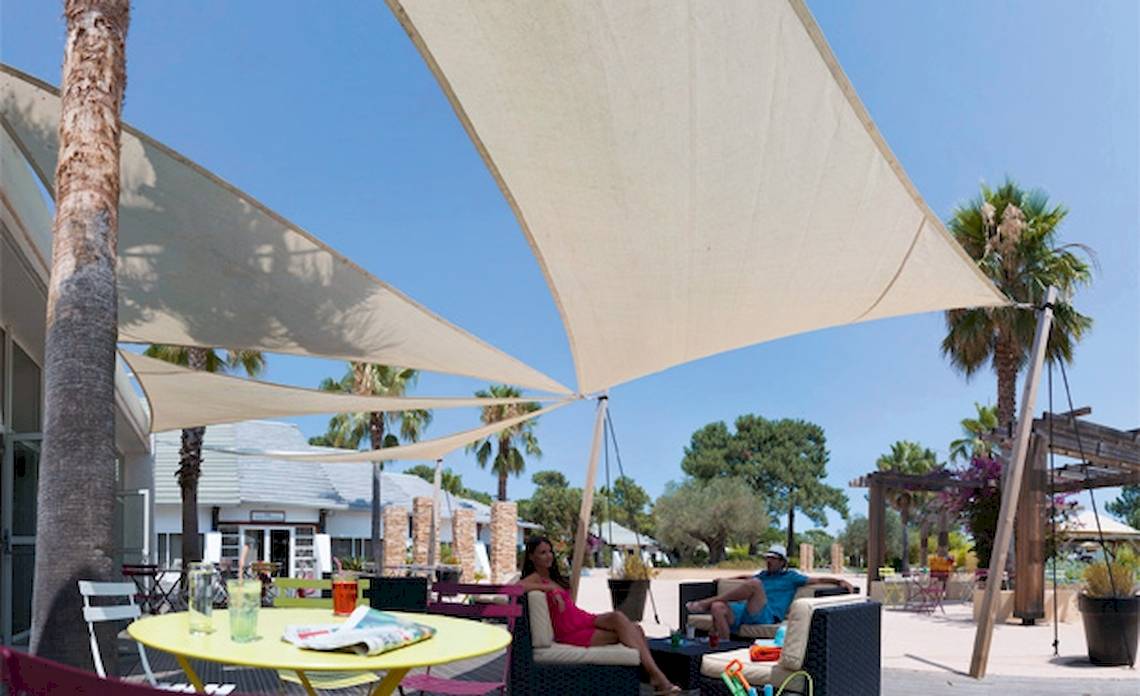 Hotelterrasse mit Sonnenschirm und Sofas, wo Gäste sich entspannen.