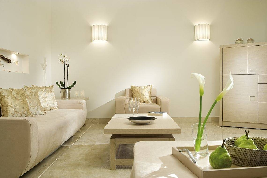 Wohnbereich im Sani Club Hotel mit beigefarbener Couch, Tisch, Kissen und Blumenvase