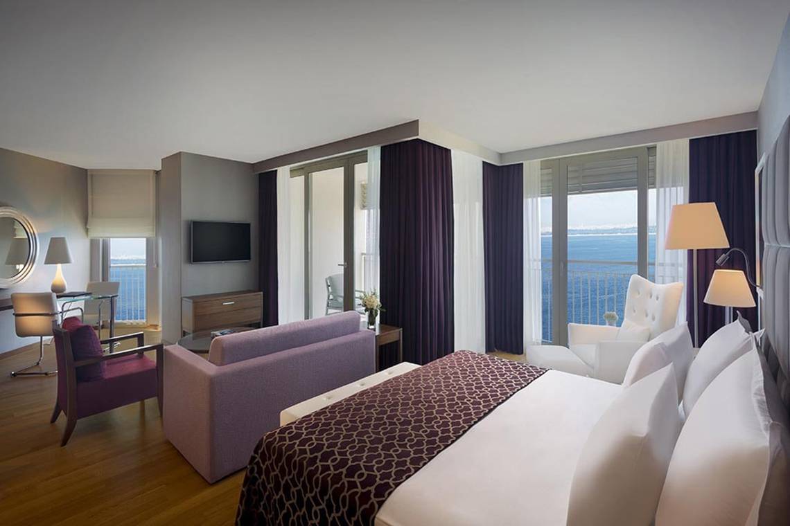Suite im Akra Hotel mit Meerblick, inklusive Bett, Sofa, Fernseher und Balkon.