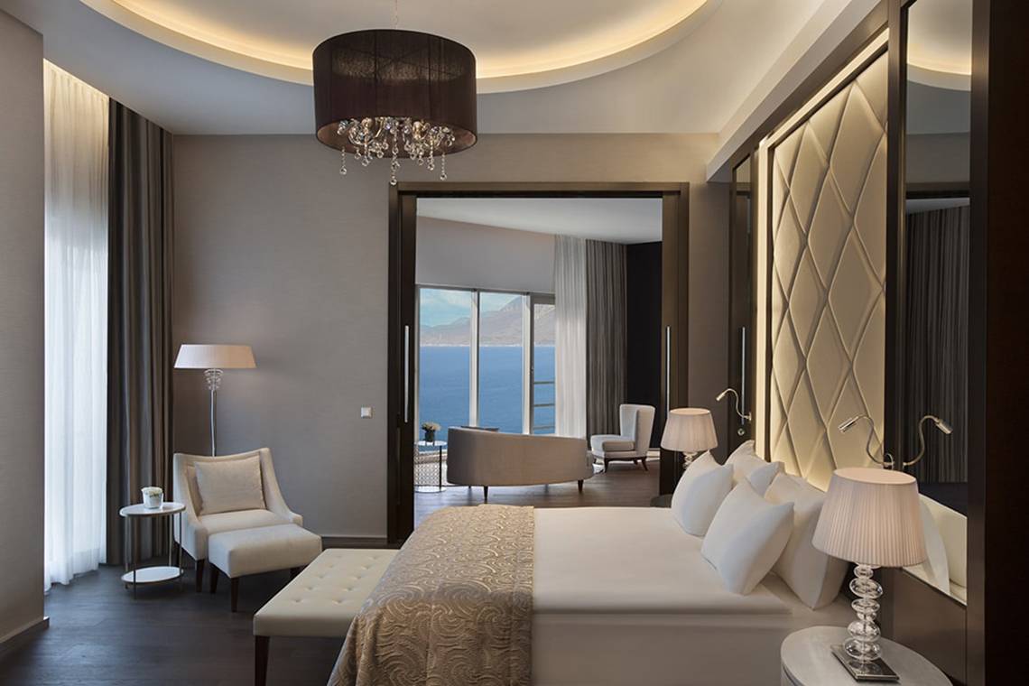 Schlafzimmer im Akra Hotel mit Blick auf das Meer, modernes Design, großem Bett und eleganten Möbeln.
