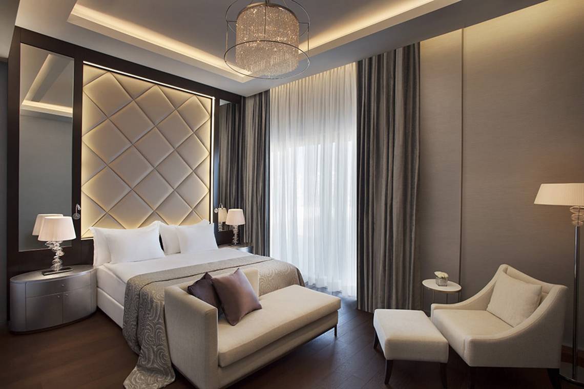 Schlafzimmer im Akra Hotel mit einem Bett, einer Couch, Stühlen und Lampen.