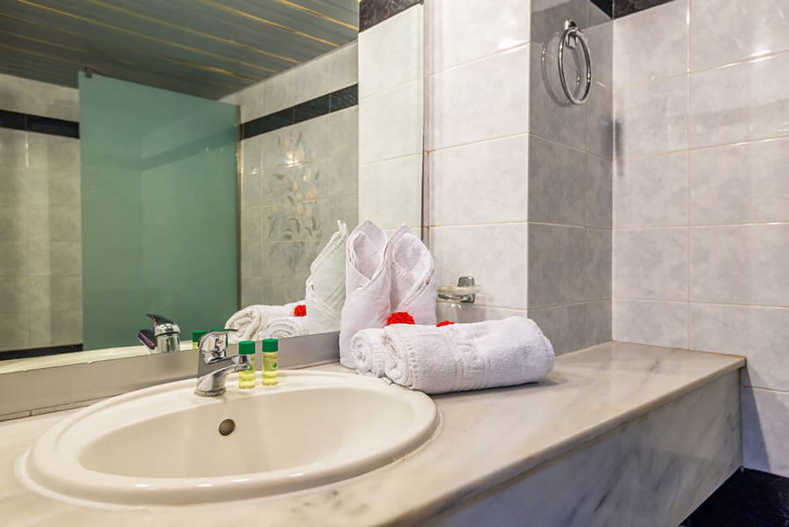 Ein Badezimmer mit einem Waschbecken, Spiegel und weißen Handtüchern.