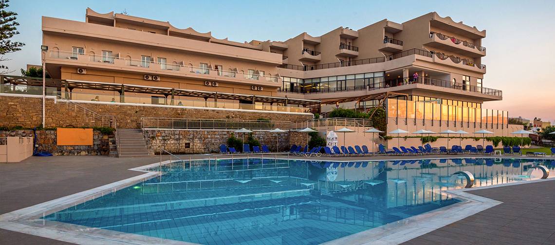 Außenbereich des Themis Beach Hotels mit Swimmingpool und Sonnenliegen.