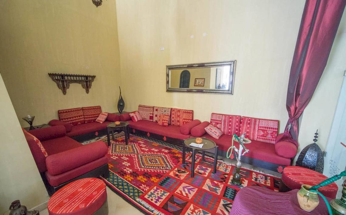 Wohnzimmer mit roten Sofas, einem Teppich und einer dekorativen Wand