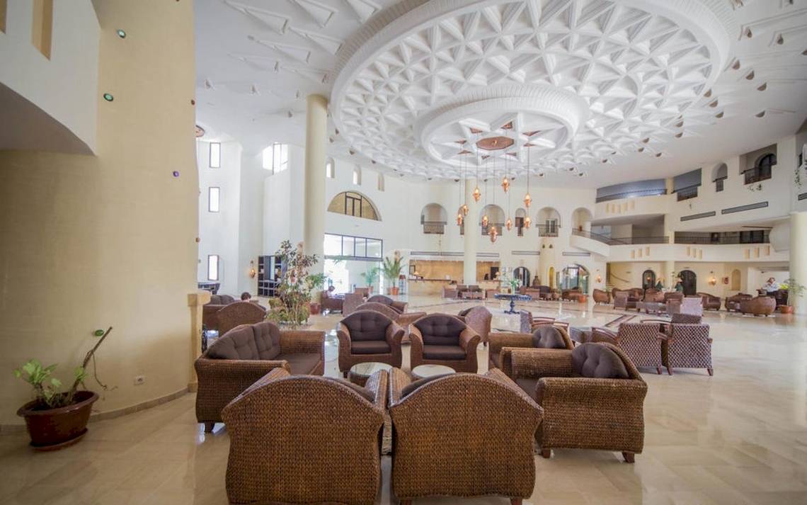 Lobby des Green Palm Hotels mit vielen Stühlen und Tischen, geometrischen Decken und Pflanzen.
