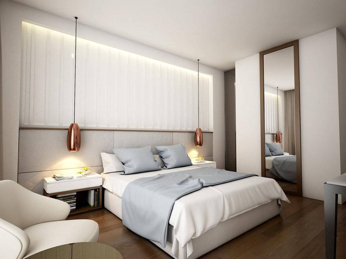 Innenansicht eines Schlafzimmers im NissiBlu Beach Resort mit weißem Bett, grauen Kissen und modernen Lampen.