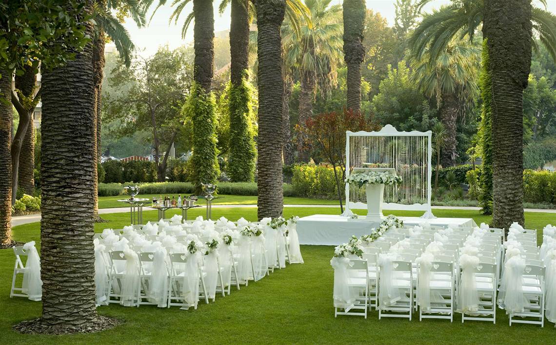 Gartenzeremonie im Swissotel Buyuk Efes Izmir mit weißen Stühlen und Blumendekoration.
