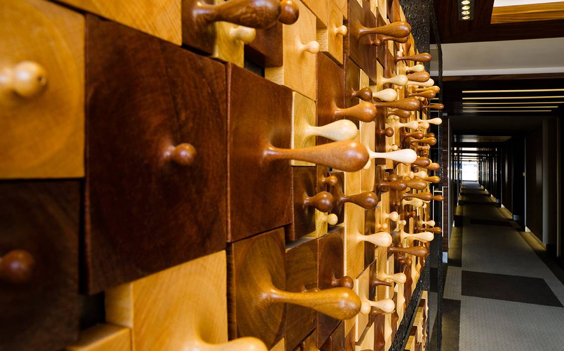 Ein langer Flur im Swissotel Buyuk Efes Izmir mit einer Wand aus Holzpaneelen, die wie Schachfiguren aussehen.