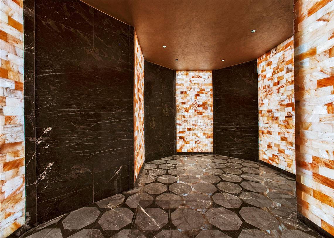 Innenraum des Maxx Royal Kemer Resorts mit schwarzen und orangefarbenen Marmorwänden und einem gepflasterten Boden.