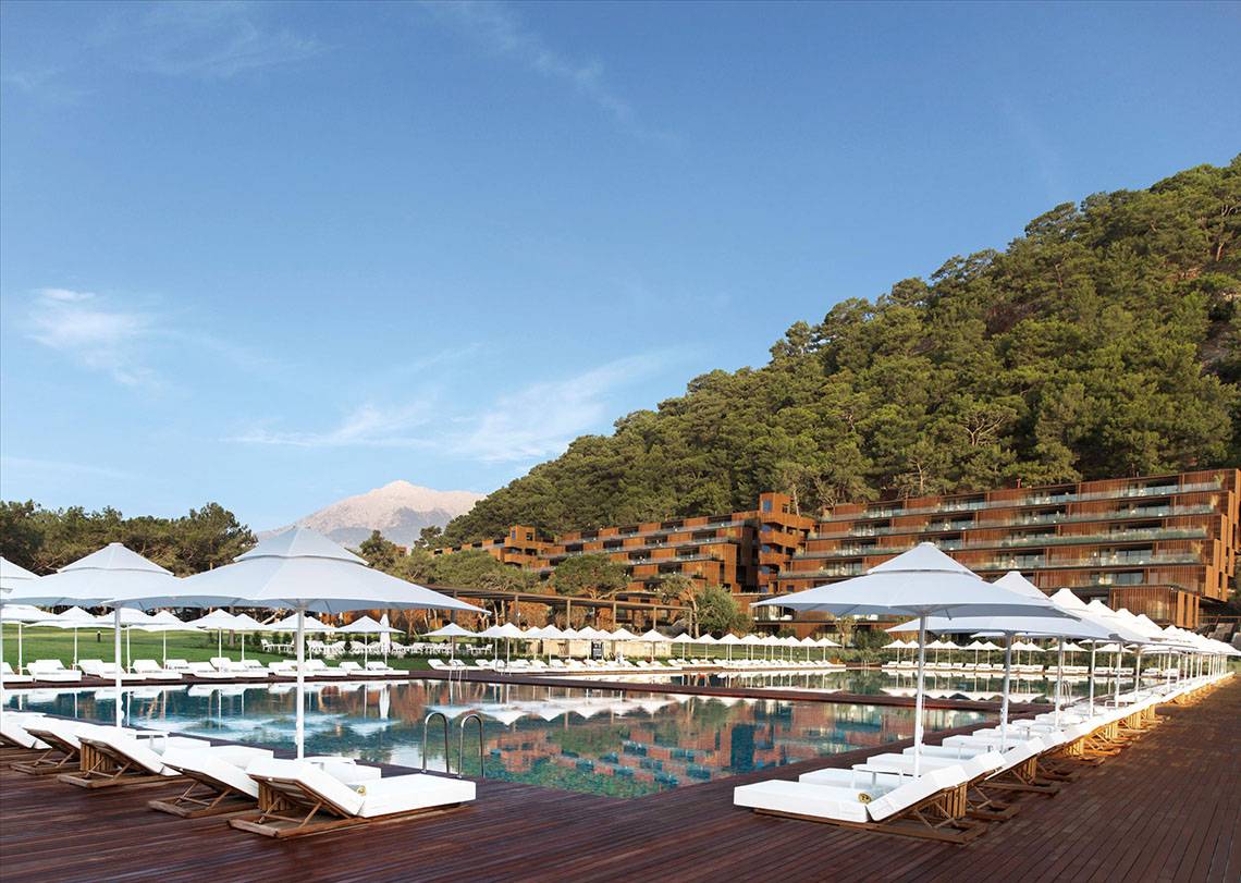 Poolbereich des Maxx Royal Kemer Resort mit vielen weißen Sonnenliegen und Sonnenschirmen.
