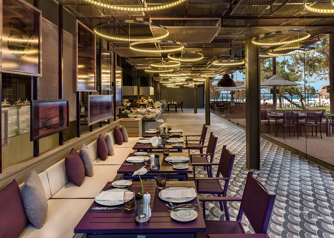 Innenansicht des Restaurants im Maxx Royal Kemer Resort mit gedeckten Tischen und Blick aufs Meer.