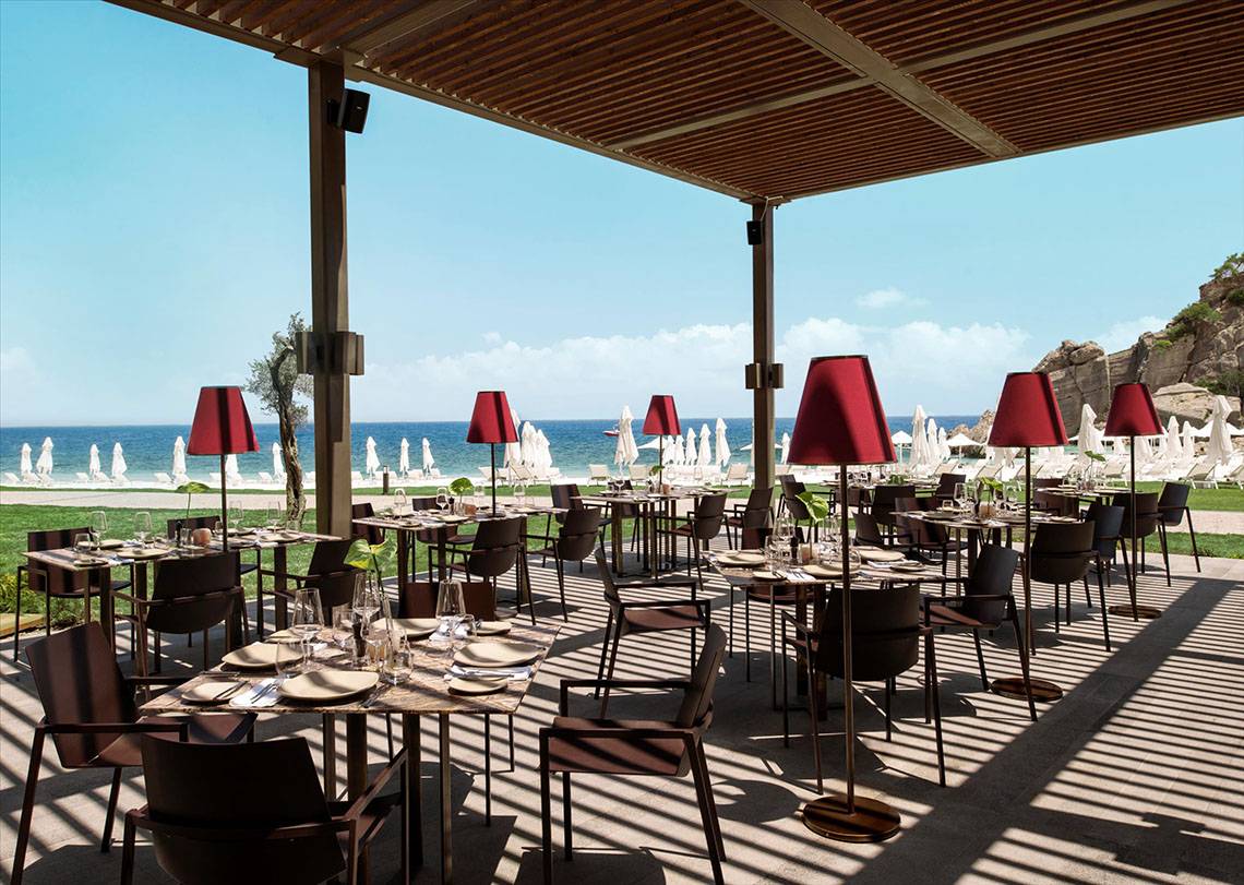 Restaurantterrasse des Maxx Royal Kemer Resorts mit Blick auf das Meer und die umliegenden Liegestühle.