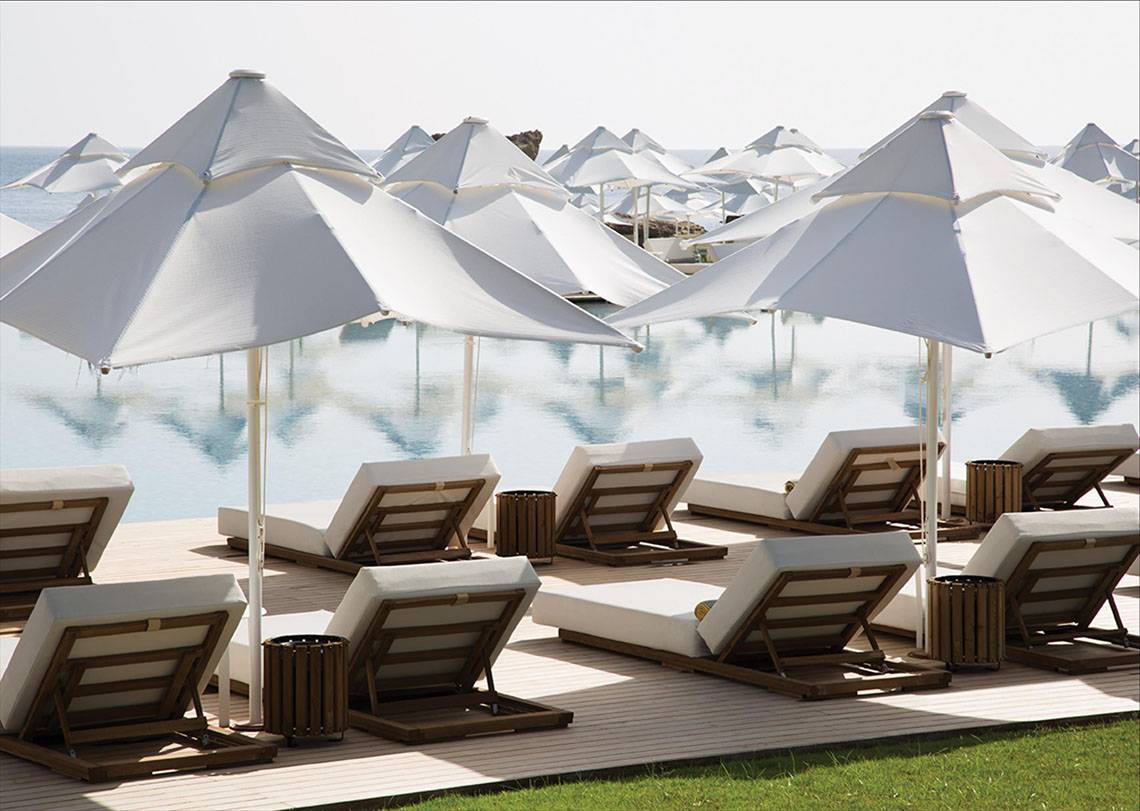 Außenbereich des Maxx Royal Kemer Resorts mit weißen Sonnenschirmen und Liegestühlen am Pool